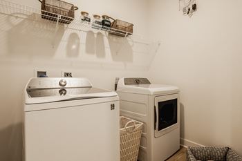 Laundry room with washer and dryer with shelves at Upper Vue Flats, Dublin, 43016